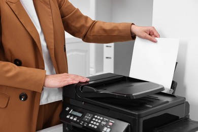 Photo of Woman using modern printer at workplace indoors, closeup