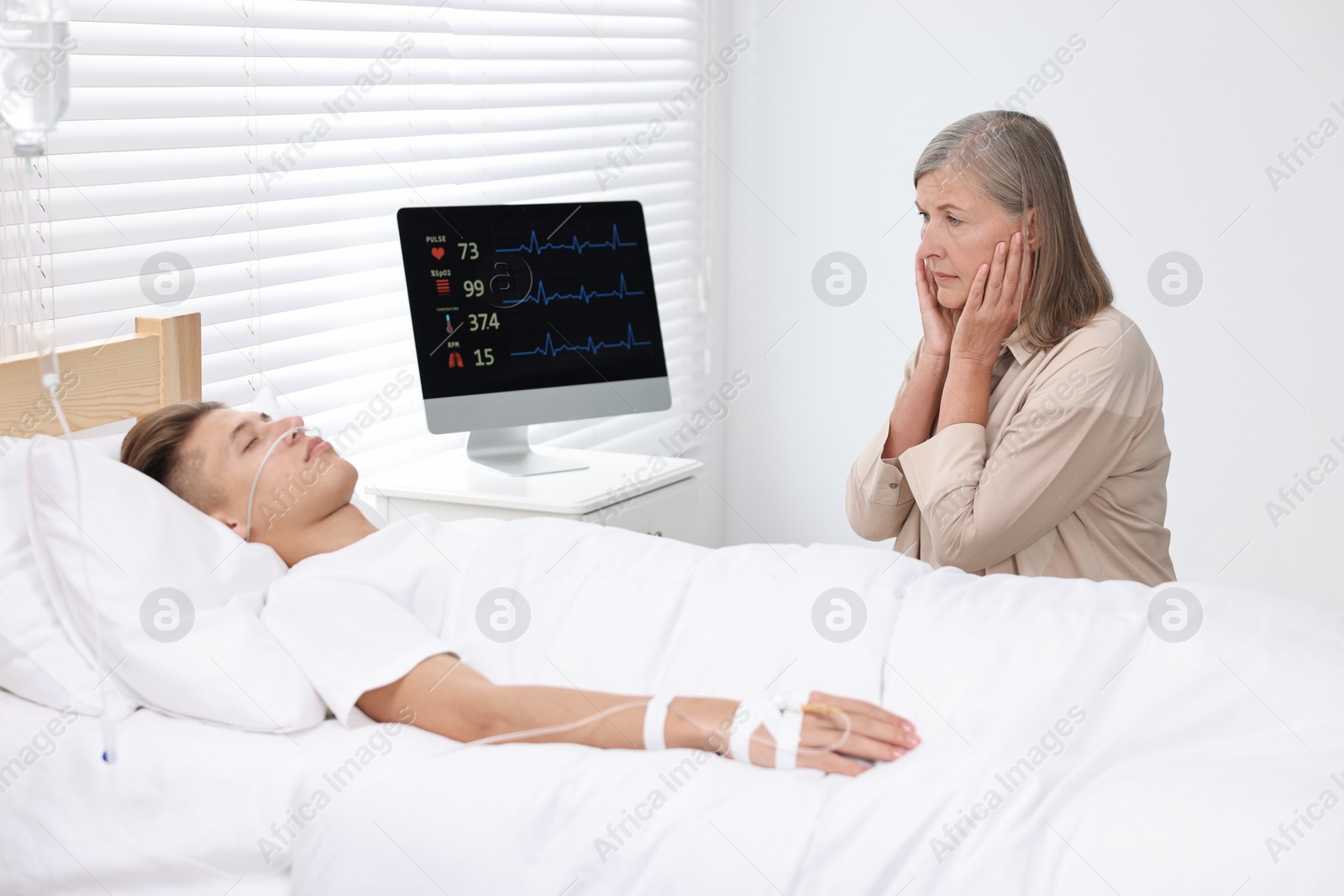 Photo of Coma patient. Sad mature woman near her unconscious son in hospital