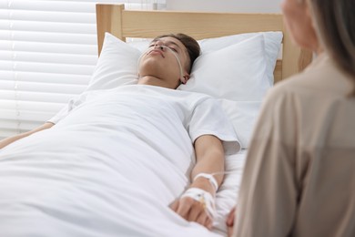 Coma patient. Sad mature woman near her unconscious son in hospital