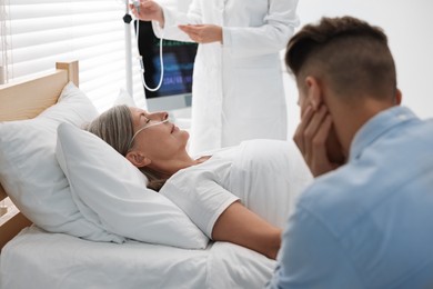 Coma patient. Sad young man near his unconscious mother in hospital