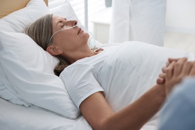 Photo of Coma patient. Man near his unconscious mother in hospital