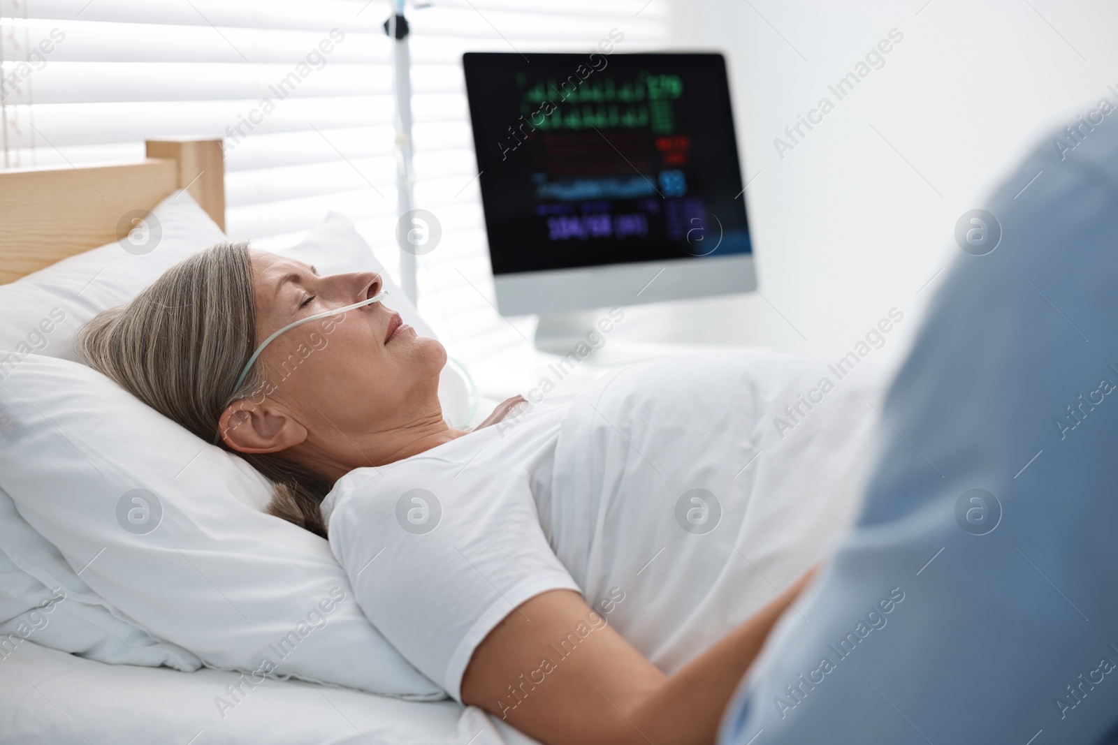 Photo of Coma patient. Man near his unconscious mother in hospital