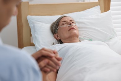 Photo of Coma patient. Man near his unconscious mother in hospital