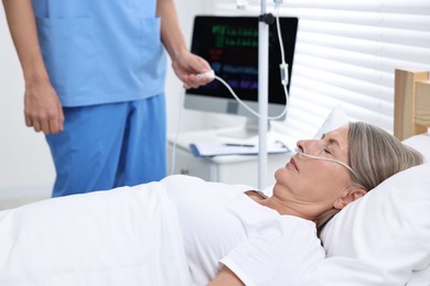 Photo of Coma patient. Doctor near unconscious mature woman in hospital, closeup