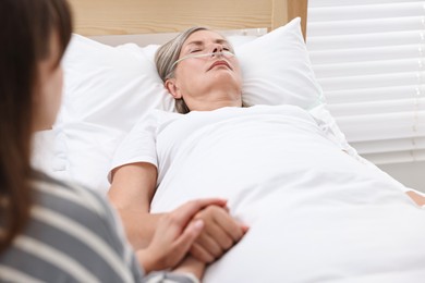 Coma patient. Woman near her unconscious mother in hospital