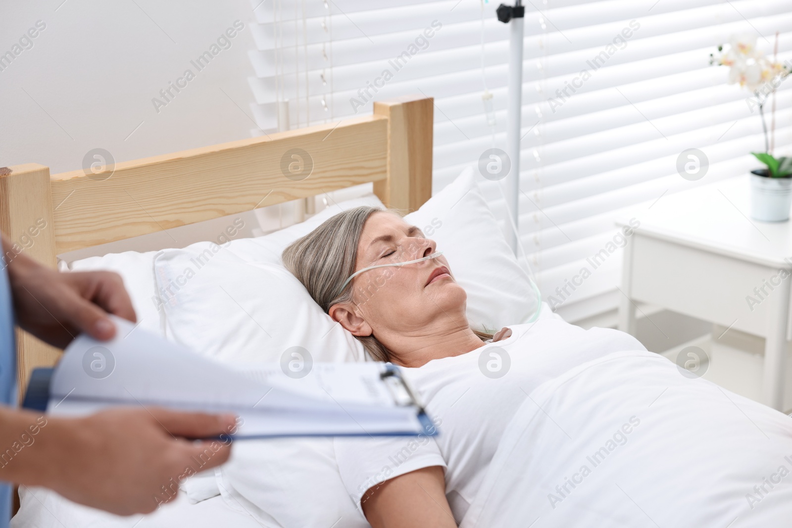 Photo of Coma patient. Doctor near unconscious mature woman in hospital, closeup