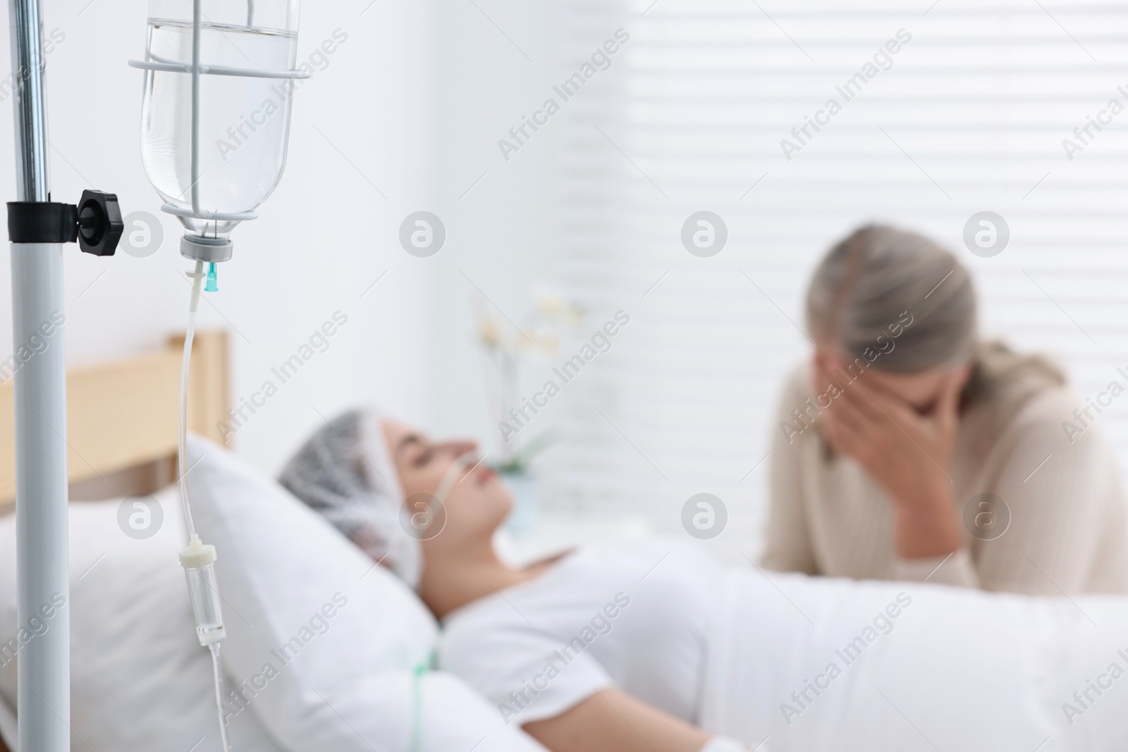 Photo of Coma patient. Sad mature woman near her unconscious daughter in hospital, selective focus