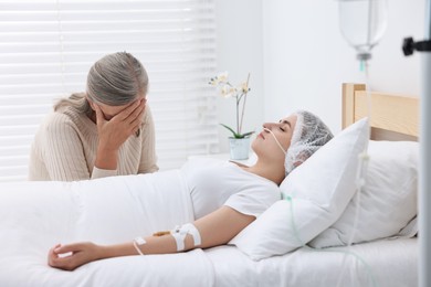 Coma patient. Sad mature woman near her unconscious daughter in hospital