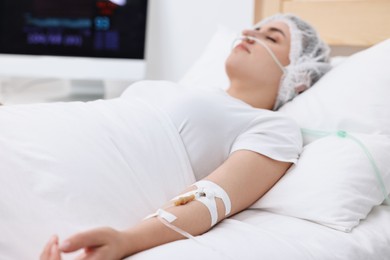 Coma patient. Woman with intravenous drip in hospital bed, selective focus