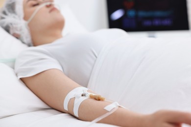 Photo of Coma patient. Woman with intravenous drip in hospital bed, selective focus