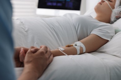 Photo of Coma patient. Man near his unconscious wife in hospital