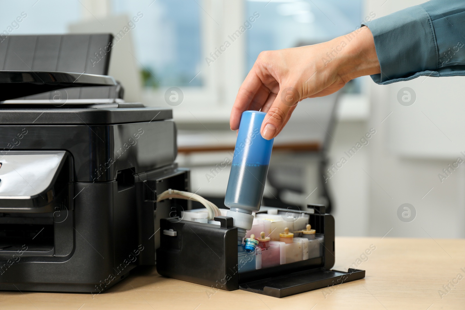 Photo of Woman refilling ink in modern printer at workplace indoors, closeup