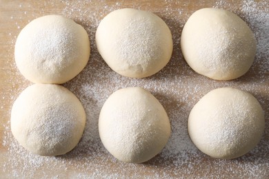 Raw dough balls on wooden table, top view