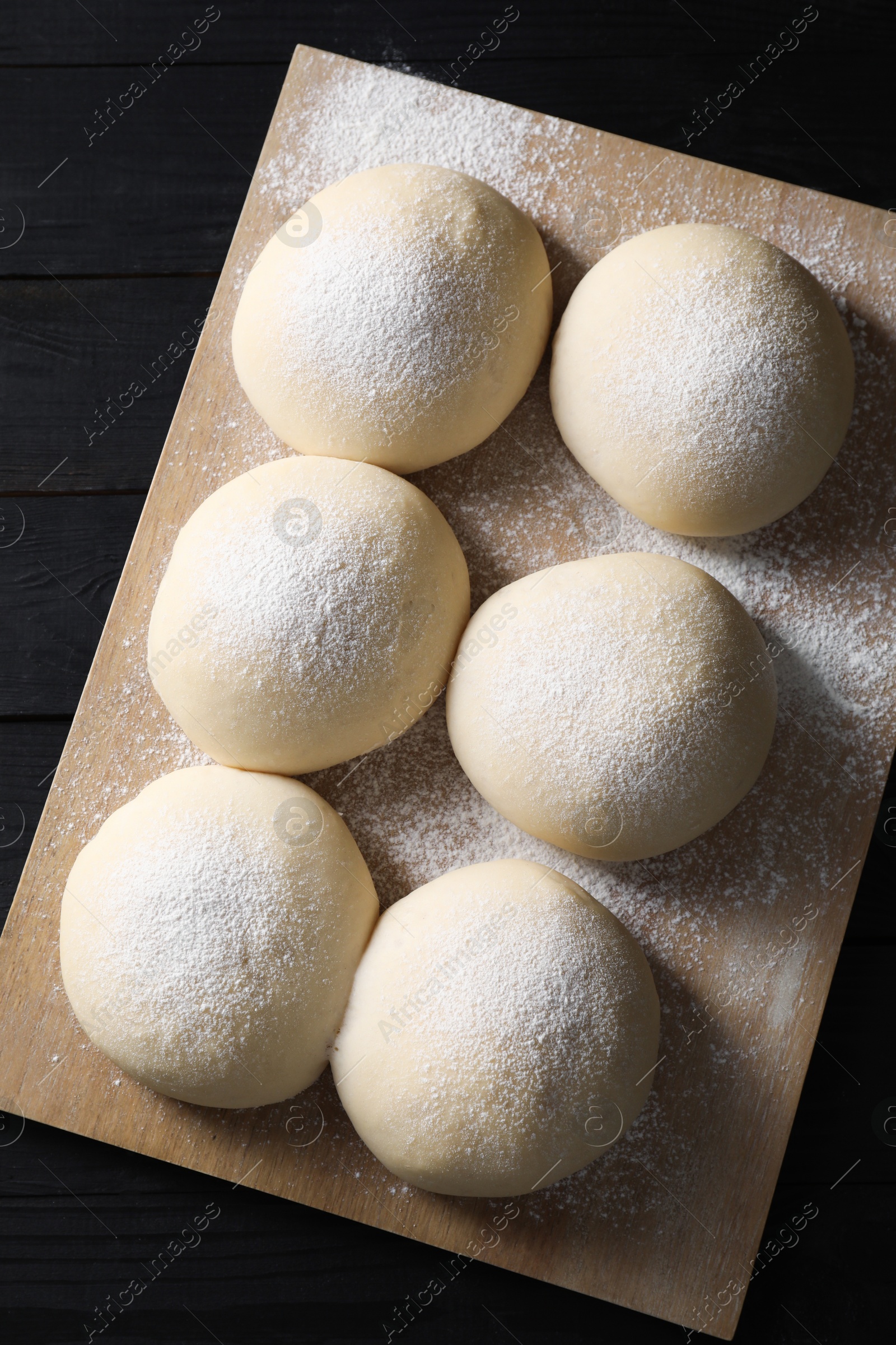 Photo of Raw dough balls on black wooden table, top view