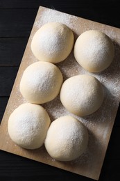 Raw dough balls on black wooden table, top view