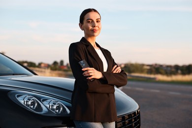 Beautiful young woman with smartphone near car outdoors