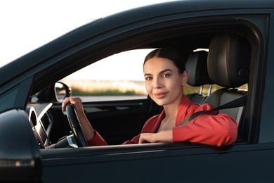 Beautiful young woman with seatbelt driving car, view from outside