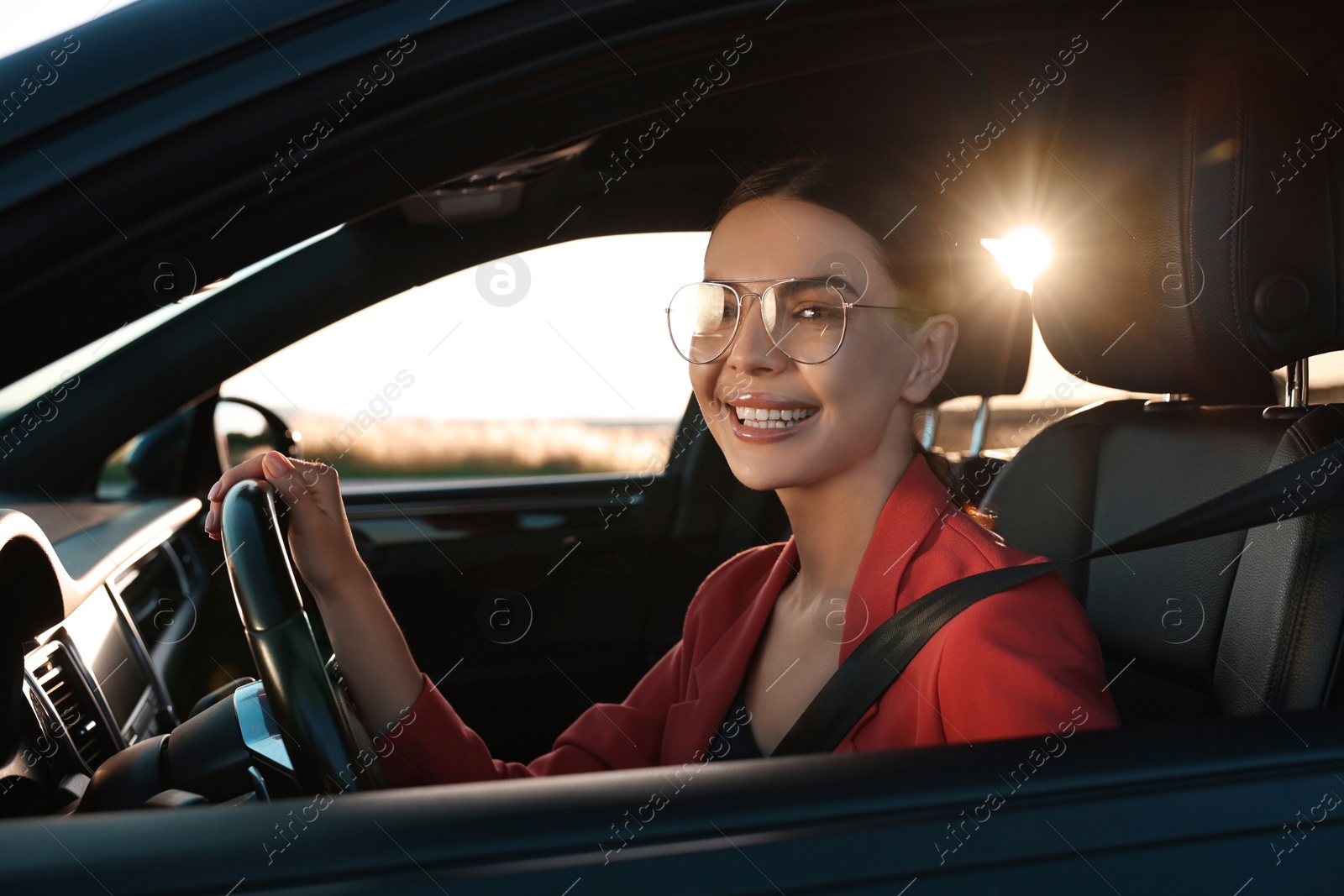 Photo of Smiling young woman with seatbelt driving car, view from outside