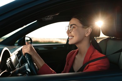 Photo of Smiling young woman with seatbelt driving car, view from outside