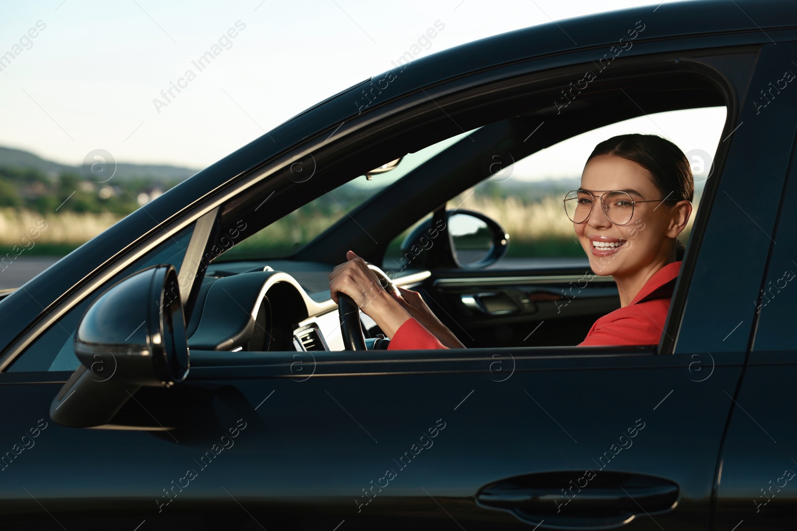 Photo of Smiling young woman with seatbelt driving car, view from outside