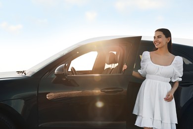 Photo of Smiling young woman near car at sunset