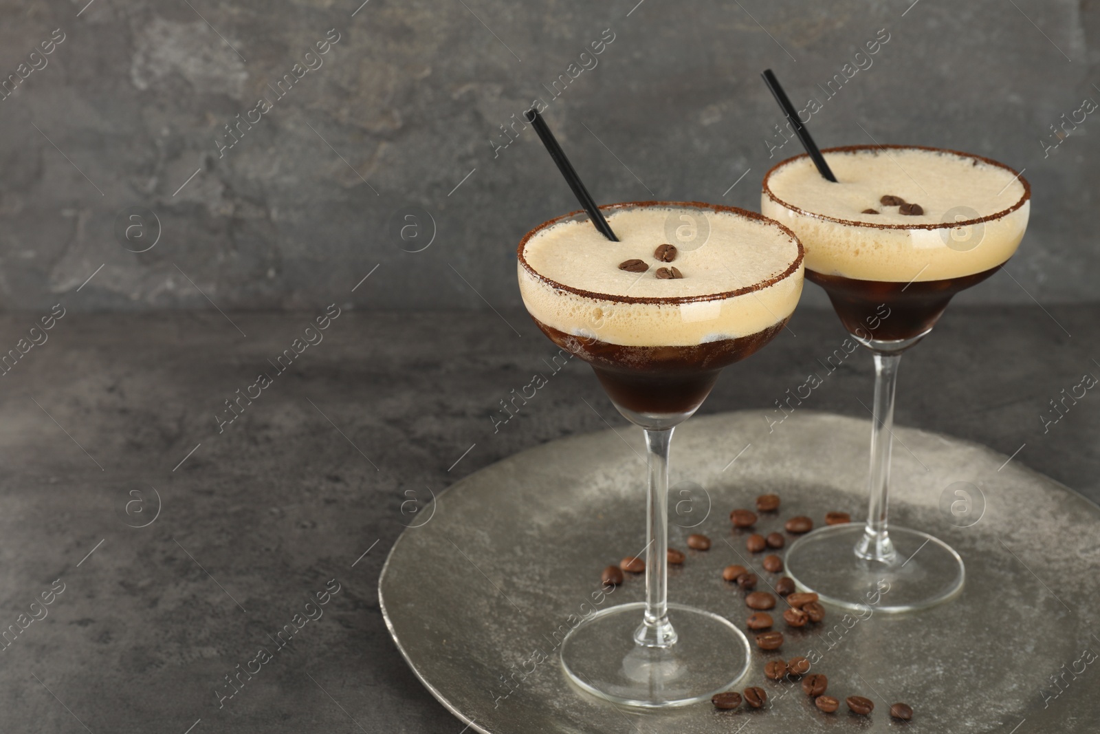 Photo of Glasses of fresh coffee cocktail on gray textured table, space for text