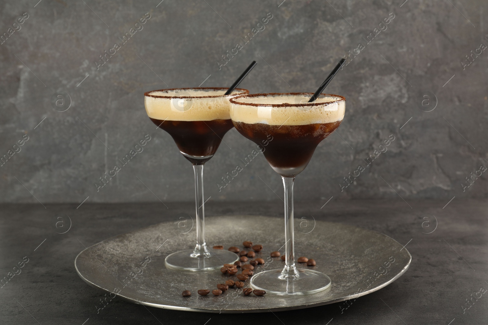 Photo of Glasses of fresh coffee cocktail on gray textured table