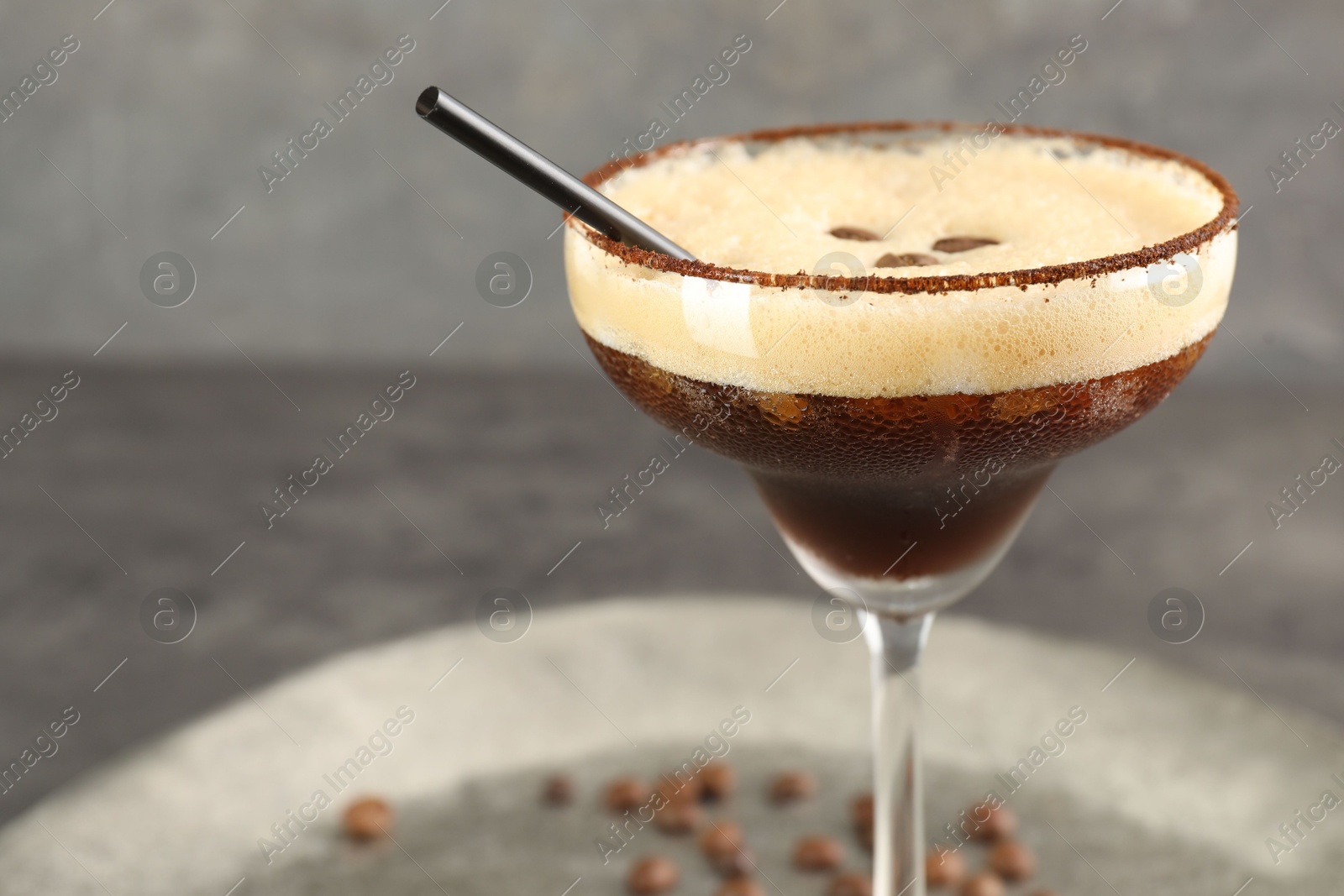 Photo of Glass of fresh coffee cocktail on gray table, closeup. Space for text