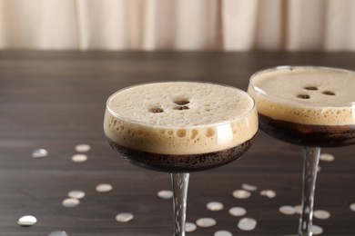 Photo of Fresh coffee cocktails in glasses and confetti on wooden table, closeup