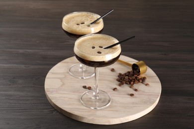 Photo of Fresh coffee cocktails in glasses and beans on wooden table