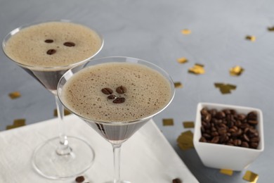 Photo of Fresh coffee cocktails in glasses, beans and confetti on grey table, closeup