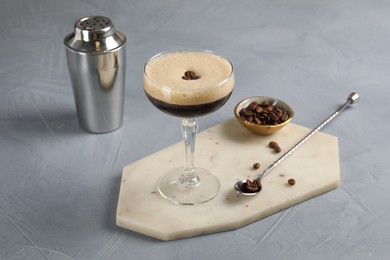 Photo of Fresh coffee cocktail in glass, beans and bartender equipment on grey table