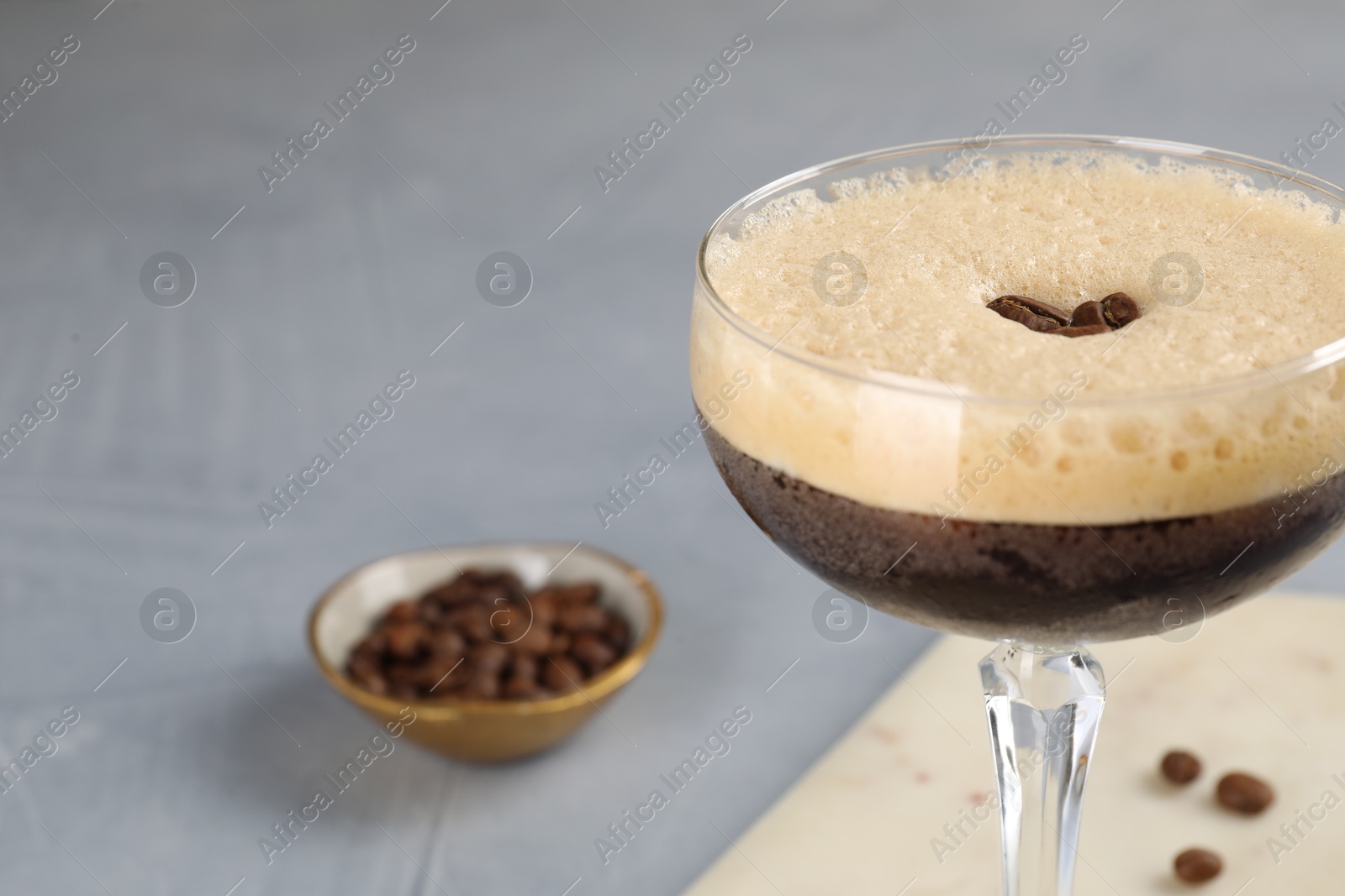 Photo of Fresh coffee cocktail in glass and beans on grey table, closeup