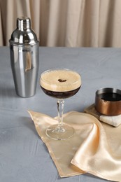 Photo of Fresh coffee cocktail in glass and shaker on grey table