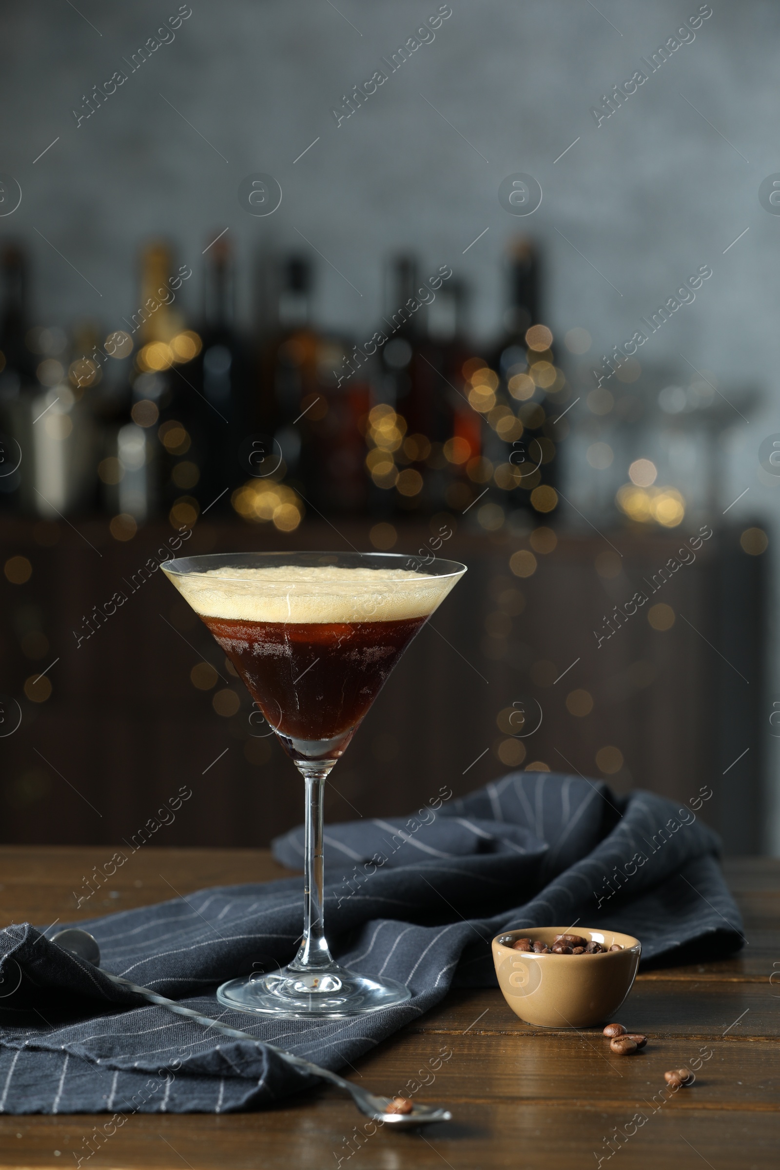 Photo of Refreshing cocktail, spoon and coffee beans on wooden table