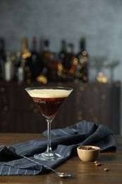 Refreshing cocktail, spoon and coffee beans on wooden table