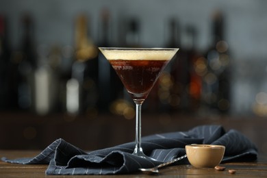 Refreshing cocktail, spoon and coffee beans on wooden table