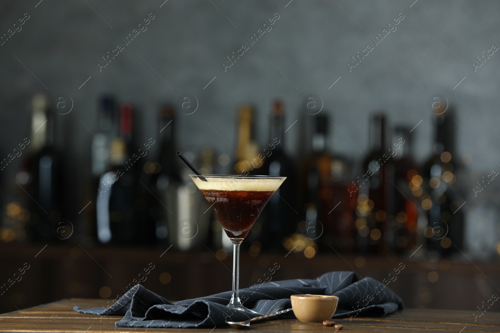 Photo of Refreshing cocktail, spoon and coffee beans on wooden table