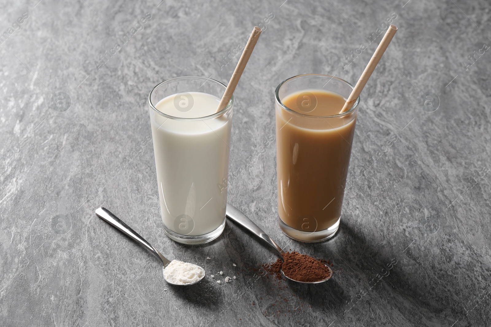 Photo of Delicious protein shakes in glasses and spoons with powder on grey table