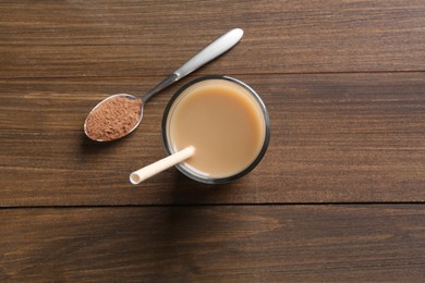 Photo of Delicious protein shake in glass and spoon with powder on wooden table, top view