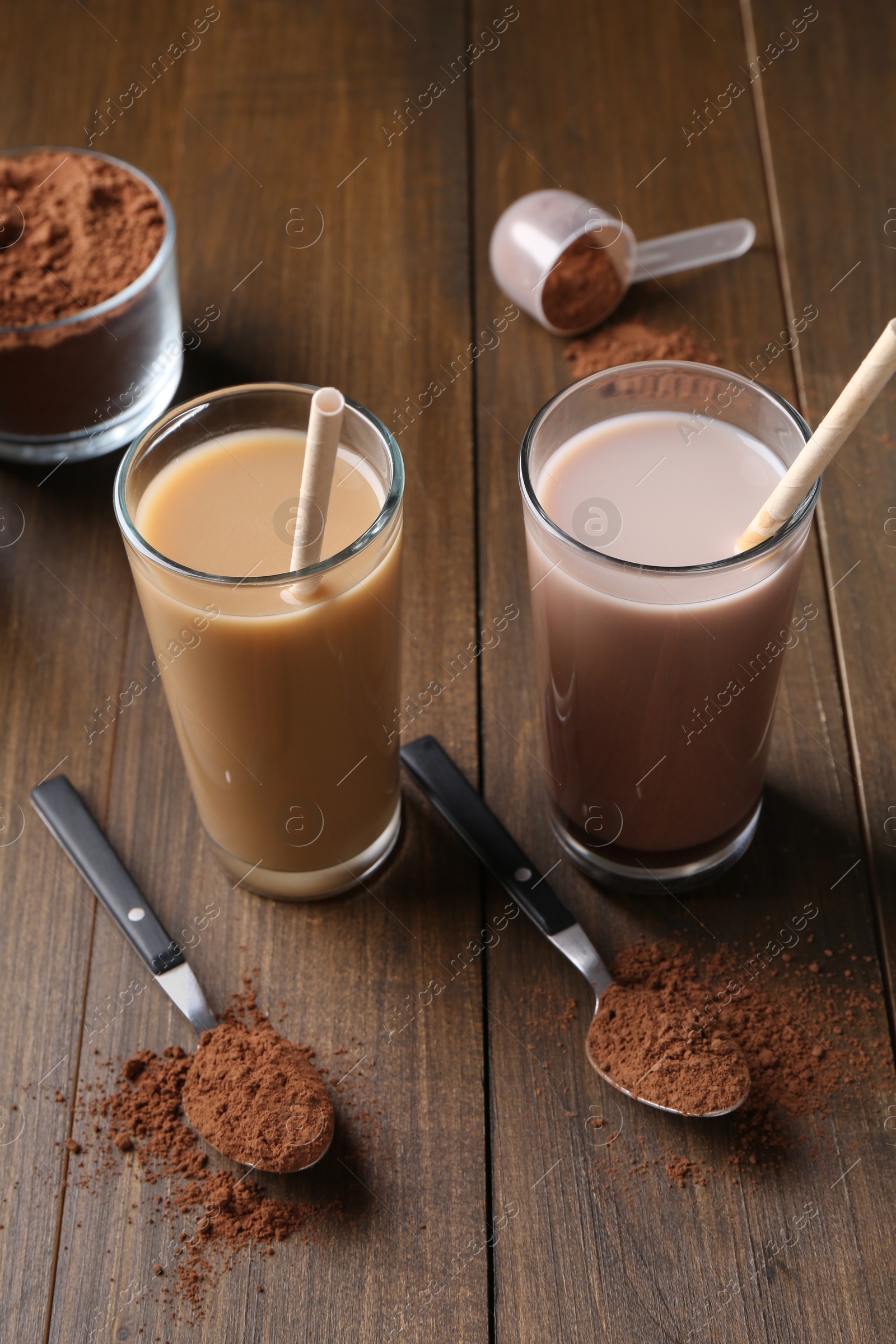 Photo of Delicious protein shakes in glasses, powder and spoons on wooden table