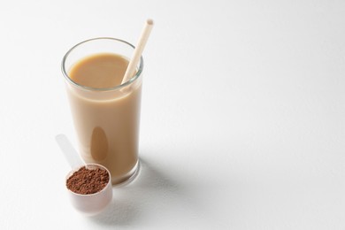 Photo of Delicious protein shake in glass and scoop with powder on white background, space for text