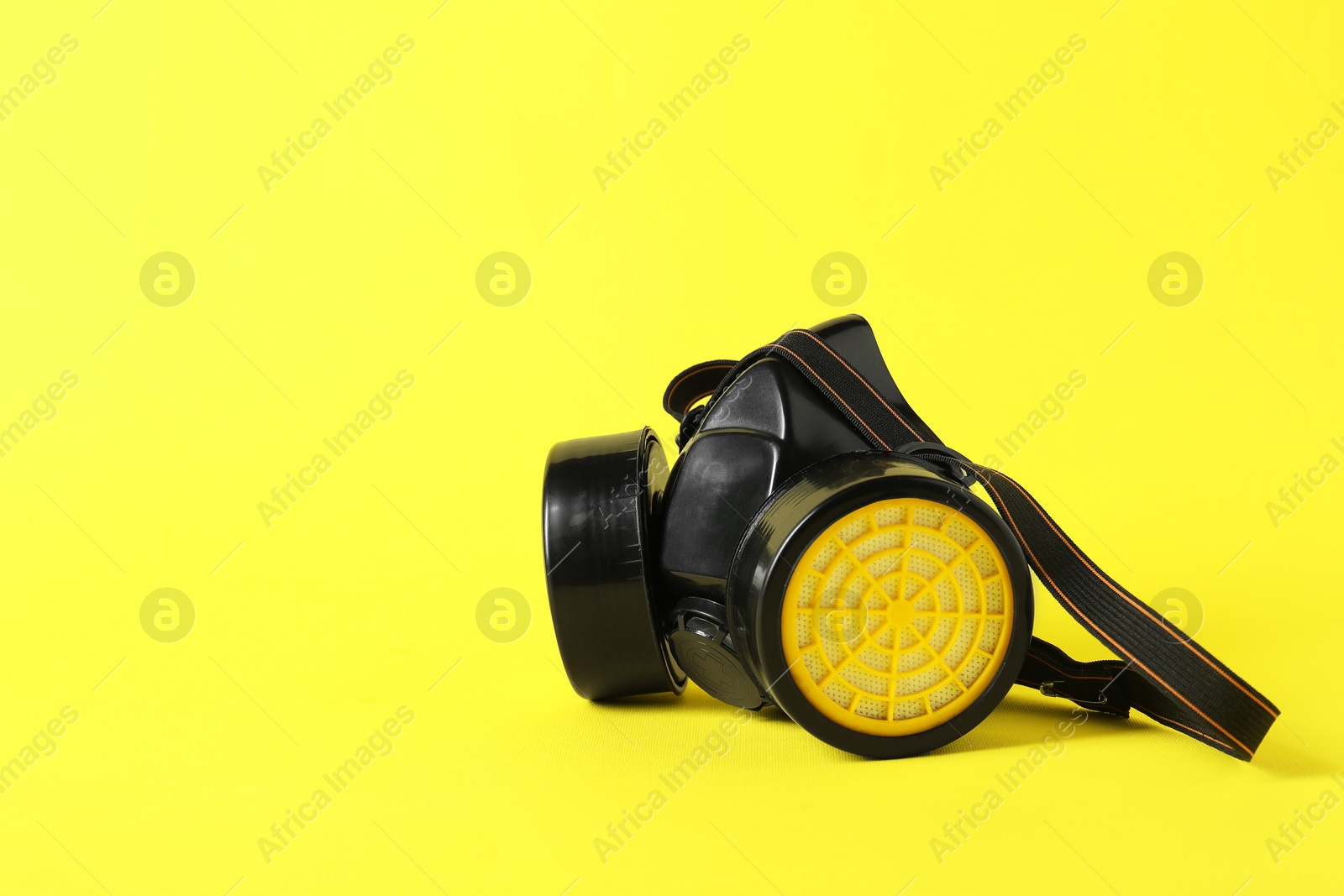 Photo of One respirator mask on yellow background, space for text