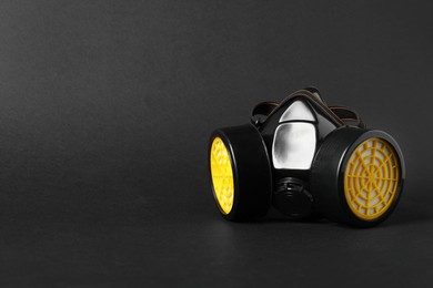 One respirator mask on black background, space for text