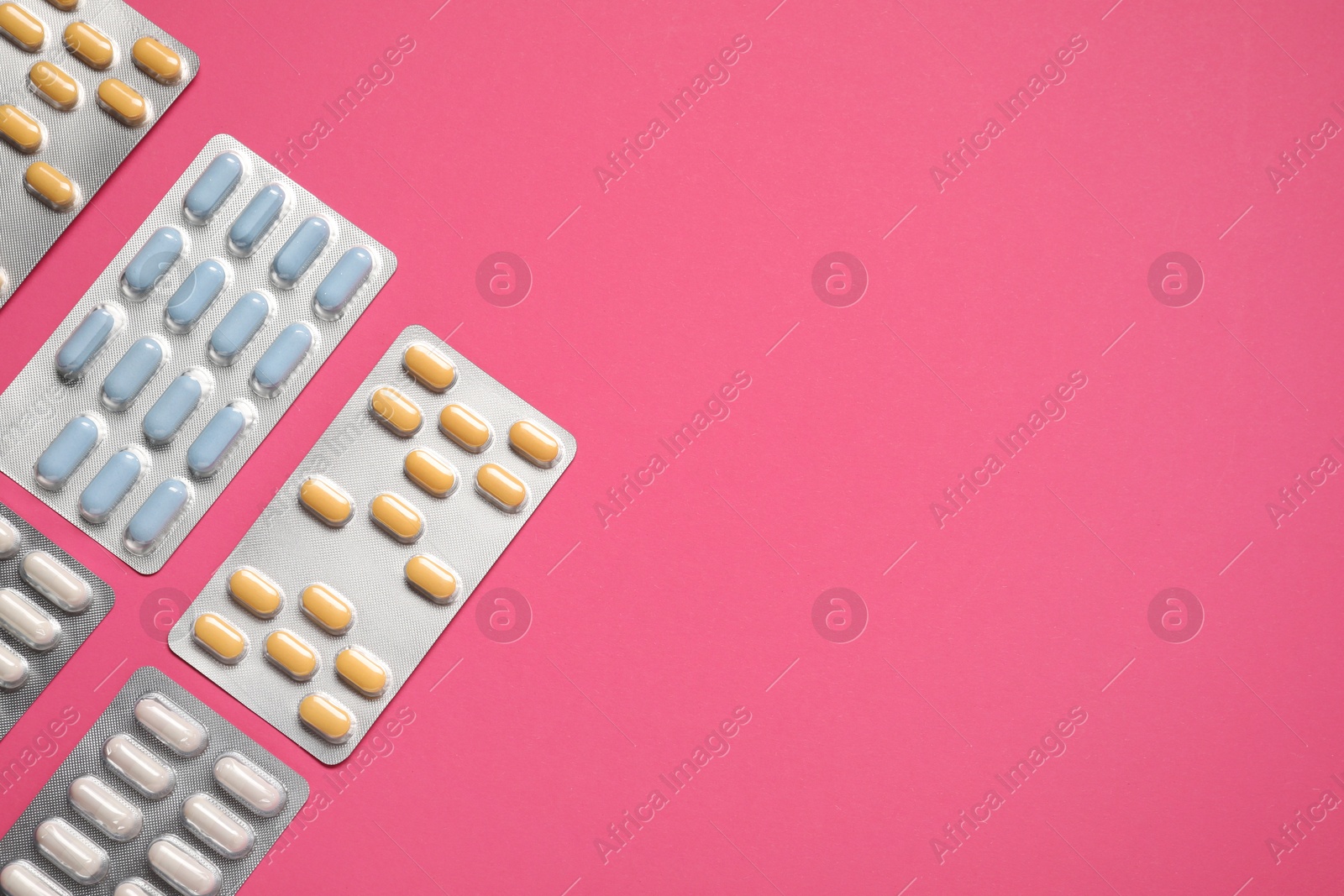 Photo of Different antibiotic pills in blisters on pink background, flat lay. Space for text