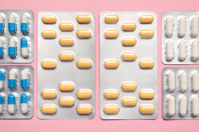 Photo of Different antibiotic pills in blisters on pink background, flat lay