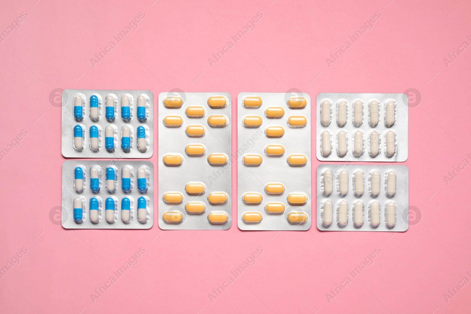 Photo of Different antibiotic pills in blisters on pink background, flat lay