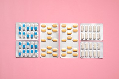 Photo of Different antibiotic pills in blisters on pink background, flat lay