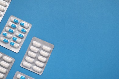 Photo of Different antibiotic pills in blisters on light blue background, flat lay. Space for text