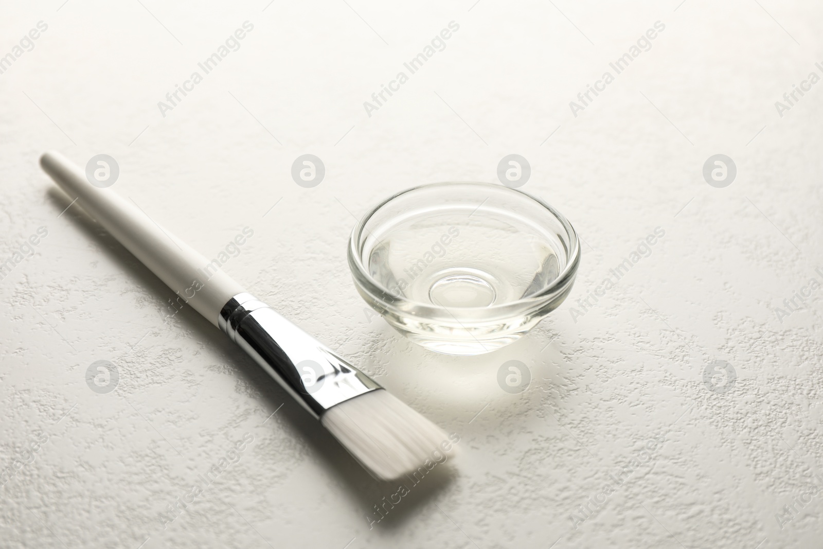 Photo of Peeling procedure. Chemical peel liquid in bowl and brush on white table